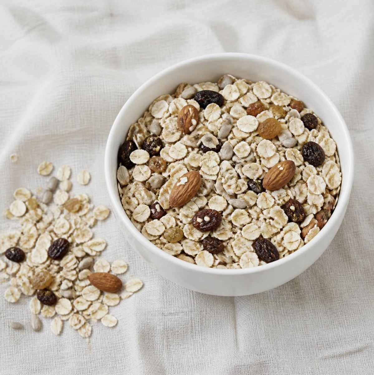 Muesli Natural Organic, untoasted muesli with oats, raisins, sultanas and almonds in a white bowl, Scoop Wholefoods Cottesloe
